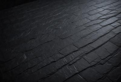 The primary subject of the image is a black leather surface, which appears to be a leather-like material or a leather-like fabric. The setting is a dark room, and the visual style is a close-up of the leather surface. The colors and mood of the image are predominantly dark and moody, with the black leather surface being the main focus.