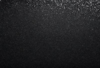 The primary subject of the image is a black background with a pattern of glittering specks. The setting is a dark room, and the visual style appears to be a combination of a photo and digital art. The colors and mood of the image are predominantly dark, with the glittering specks adding a touch of brightness and interest to the overall atmosphere.