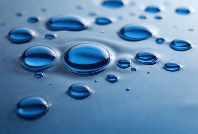 The primary subject of the image is a close-up of a blue surface, possibly a table or a piece of fabric, with numerous small blue bubbles on it. The setting appears to be a room or a similar indoor environment. The visual style of the image is a close-up, which emphasizes the details of the bubbles. The colors and mood of the image are predominantly blue, creating a calm and serene atmosphere.
