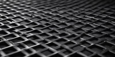 The primary subject of the image is a close-up of a black mesh or woven material. The setting is a black background, which provides a stark contrast to the mesh. The visual style is a detailed, up-close view of the mesh, showcasing its intricate pattern. The colors and mood of the image are predominantly dark, with the black mesh and background creating a moody atmosphere.