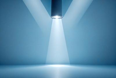 The primary subject of the image is a light source, which appears to be a spotlight or a light bulb. The light source is shining brightly, creating a strong and focused beam of light. The setting is a white background, which provides a clean and minimalistic environment for the light source to stand out. The visual style of the image is a close-up of the light source, emphasizing its brightness and intensity. The colors and mood of the image are predominantly white, giving it a clean and modern appearance.