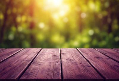The primary subject of the image is a wooden bench. The setting is a forest, with trees and sunlight visible in the background. The visual style is a photo, capturing the natural environment and the wooden bench. The colors and mood of the image are predominantly green, with the sunlight creating a warm and inviting atmosphere.