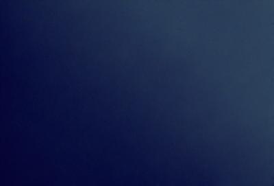 The primary subject of the image is a large, dark blue sky. The setting is a vast, open space with no visible landmarks or objects. The visual style is a natural, untouched landscape. The colors and mood are predominantly dark and moody, with the blue sky serving as the main focal point.