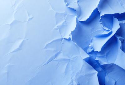 The primary subject of the image is a piece of blue paper with a wrinkled texture. The setting is a blue background, and the visual style appears to be a photo. The colors and mood of the image are predominantly blue, creating a calm and serene atmosphere.