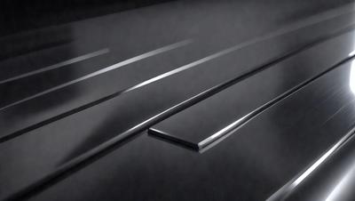 The primary subject of the image is a metal surface, possibly a metal floor or a metal wall. The setting is a dark room, which creates a moody atmosphere. The visual style is a black and white photo, giving the image a classic and timeless appearance. The colors and mood of the image are predominantly dark, with the metal surface being the main focal point.