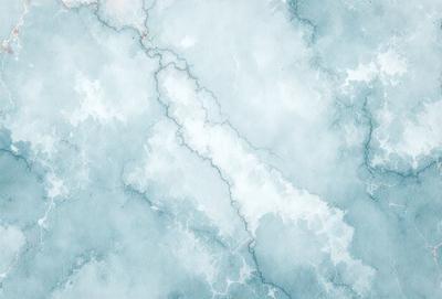 The primary subject of the image is a blue and white marble-like pattern. The setting is a blue and white marble-like surface, which could be a wall or a countertop. The visual style is a digital art or illustration, as the pattern appears to be hand-drawn. The colors and mood of the image are predominantly blue and white, creating a calm and serene atmosphere.