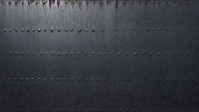 The primary subject of the image is a large, dark, and textured surface. The setting appears to be a black metal wall, possibly a door or a piece of art. The visual style of the image is a close-up of the surface, showcasing its intricate details. The colors and mood of the image are dark and moody, with the black metal wall creating a sense of depth and mystery.