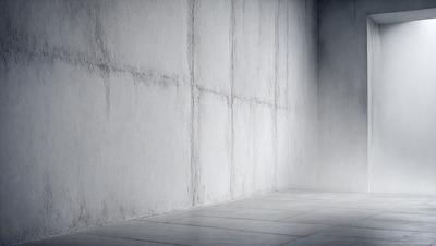 The primary subject of the image is a white wall with a concrete texture. The setting is a room with a concrete floor. The visual style is a black and white photo, which gives the image a classic and timeless appearance. The dominant colors are white and gray, creating a clean and minimalist atmosphere.