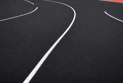 The primary subject of the image is a white line on a black surface, which appears to be a track or a road. The setting is an outdoor environment, possibly a track or a road. The visual style is a photo, capturing the white line on the black surface. The colors and mood of the image are predominantly black and white, giving it a classic and timeless appearance.