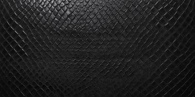 The primary subject of the image is a close-up of a black leather material. The setting is a dark background, which contrasts with the leather material. The visual style is a close-up of the leather, showcasing its texture and pattern. The colors and mood of the image are predominantly dark, with the black leather material being the main focus.