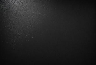 The primary subject of the image is a black background with a few white specks. The setting is a dark room, and the visual style is a black and white photo. The colors and mood of the image are predominantly dark and moody, with the white specks adding a touch of contrast.