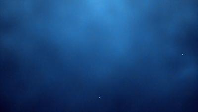 The primary subject of the image is a blue sky with a few clouds. The setting is a vast, open space with no visible landmarks or objects. The visual style is a natural, outdoor scene. The colors and mood are predominantly blue, creating a calm and serene atmosphere.