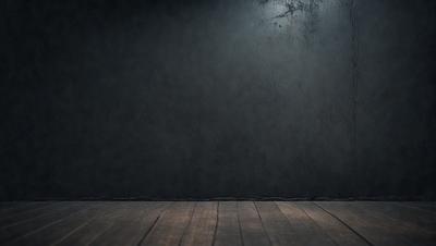 The primary subject of the image is a wooden floor with a black wall in the background. The setting appears to be a dark room, possibly a theater or a room with a black backdrop. The visual style of the image is a photo, capturing the wooden floor and the black wall in a dark environment. The colors in the image are predominantly black and brown, creating a moody atmosphere.