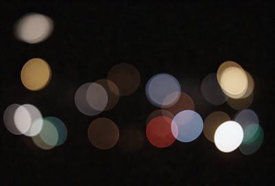 The primary subject of the image is a cityscape at night, with a focus on the lights and reflections. The setting is a dark night with a city skyline in the background. The visual style is a combination of a photo and digital art, creating a unique and artistic representation of the city at night. The colors and mood are predominantly dark and moody, with the lights and reflections creating a sense of depth and atmosphere.