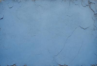 The primary subject of the image is a blue wall with a cracked and chipped surface. The setting is a room with a blue background. The visual style is a close-up of the blue wall, showcasing its texture and imperfections. The colors and mood of the image are predominantly blue, creating a calm and serene atmosphere.
