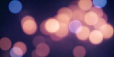 The primary subject of the image is a brightly lit scene with a focus on a pattern of lights. The setting appears to be a dark room, and the visual style is a combination of a photo and digital art. The dominant colors in the image are orange and blue, creating a warm and inviting atmosphere.