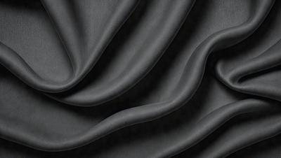 The primary subject of the image is a close-up of a black fabric, possibly a piece of clothing or a curtain. The setting is a dark background, which emphasizes the fabric's texture and pattern. The visual style is a close-up, which allows for a detailed view of the fabric. The colors and mood of the image are predominantly dark, with the black fabric being the main focus.
