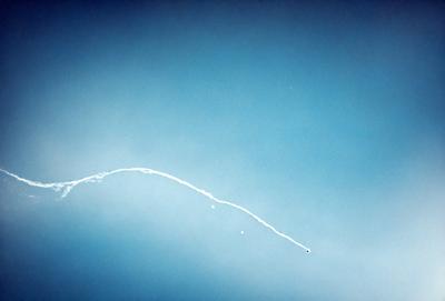 The primary subject of the image is a rocket or missile flying through the sky. The setting is a clear blue sky, which provides a contrasting backdrop for the rocket. The visual style of the image is a photo, capturing the rocket's trajectory in the sky. The colors in the image are predominantly blue, creating a sense of calmness and tranquility.