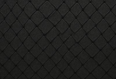 The primary subject of the image is a black and white patterned surface, which appears to be a black leather material. The setting is a close-up of the pattern, showcasing the intricate design. The visual style is a combination of a photo and a digital art, as the pattern is both detailed and well-defined. The colors and mood of the image are predominantly black and white, giving it a classic and elegant appearance.