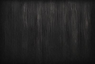 The primary subject of the image is a wooden surface, possibly a wall or a piece of furniture. The setting is a dark room, which creates a moody atmosphere. The visual style is a close-up of the wooden surface, showcasing its texture and details. The colors in the image are predominantly dark, with the wooden surface being the main focus.