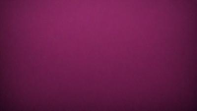The primary subject of the image is a purple background. The setting is a dark room, and the visual style is a close-up of the purple wall. The colors and mood of the image are predominantly purple, creating a calm and serene atmosphere.