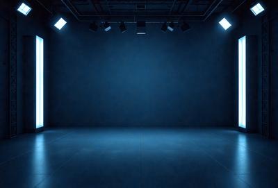 The primary subject of the image is a large, empty room with a blue wall. The setting is a darkened room with a stage, and the visual style is a black and white photo. The dominant colors are blue and black, creating a moody atmosphere.