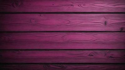 The primary subject of the image is a wooden wall with a purple tint. The setting is a room with a wooden floor. The visual style is a close-up of the wooden wall, showcasing its texture and color. The dominant colors are purple and brown, creating a warm and cozy atmosphere.