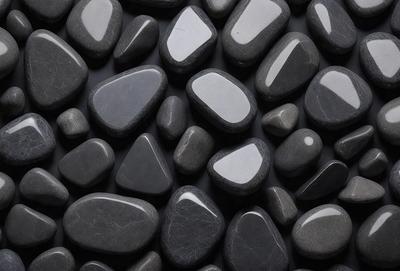 The primary subject of the image is a collection of black rocks, which are arranged in a visually appealing manner. The setting is a black background, which contrasts with the rocks, making them stand out. The visual style is a close-up of the rocks, showcasing their unique shapes and textures. The colors and mood of the image are predominantly dark, with the black rocks being the main focus.