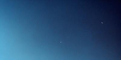 The primary subject of the image is the moon, which is seen in the sky against a backdrop of a blue sky. The visual style of the image is a painting, which gives it a more artistic and creative appearance. The colors and mood of the image are predominantly blue, creating a serene and peaceful atmosphere.