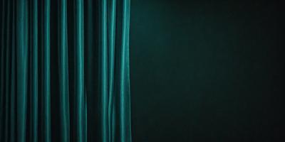 The primary subject of the image is a curtain, which is hanging in front of a dark background. The curtain is blue and appears to be a part of a stage or theater setting. The visual style of the image is a photo, capturing the curtain's texture and color. The overall atmosphere of the image is dramatic and moody, with the dark background emphasizing the curtain's presence.