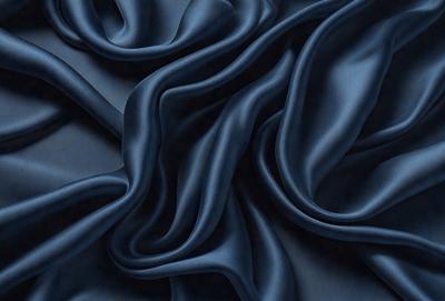 The primary subject of the image is a blue fabric, which is the main object, scene, or focus of the image. The setting or background is a dark blue surface, and the visual style is a photo. The colors and mood of the image are predominantly dark blue, creating a moody and dramatic atmosphere.