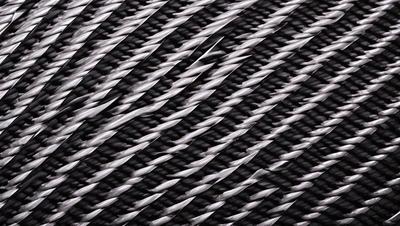 The primary subject of the image is a close-up of a black and white rope. The setting is a black background, which creates a striking contrast with the rope. The visual style is a close-up of the rope, emphasizing its texture and pattern. The colors and mood of the image are predominantly black and white, giving it a classic and timeless appearance.