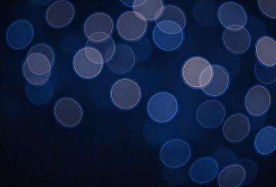 The primary subject of the image is a blue background with a pattern of white circles. The setting appears to be a nighttime scene, possibly a dark room or a night sky. The visual style of the image is a combination of a photo and digital art, creating a unique and captivating atmosphere. The dominant colors are blue and white, with the white circles creating a sense of depth and contrast against the darker blue background.