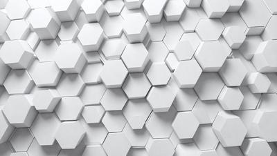 The primary subject of the image is a white wall with a pattern of white hexagons. The setting is a white room, and the visual style is a close-up of the wall. The dominant colors are white, and the overall atmosphere is clean and minimalistic.