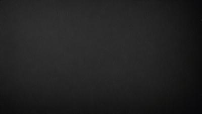 The image is a black and white photo of a dark background. The primary subject is a large, empty space with no visible objects or details. The setting is a black background, which creates a stark contrast with the subject. The visual style is a black and white photo, giving the image a classic and timeless appearance. The colors and mood are predominantly dark and moody, with the black background emphasizing the emptiness of the space.