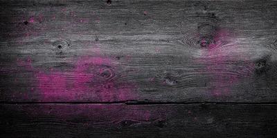 The primary subject of the image is a wooden surface with a pink substance on it. The setting appears to be a room with a wooden floor. The visual style of the image is a close-up of the wooden surface, which gives a sense of texture and detail. The colors and mood of the image are predominantly pink, creating a warm and inviting atmosphere.