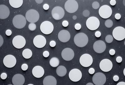 The primary subject of the image is a pattern of white circles on a gray background. The circles are arranged in various sizes and shapes, creating a visually interesting and unique design. The setting appears to be a black surface, which contrasts with the white circles, making them stand out even more. The visual style of the image is a combination of digital art and illustration, as it showcases a creative and artistic approach to design. The overall atmosphere of the image is calm and serene, with the white circles providing a sense of harmony and balance.