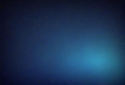 The primary subject of the image is a blue sky with a few clouds. The setting is a dark blue background, which contrasts with the lighter blue of the sky. The visual style is a photo, capturing the beauty of the sky. The colors and mood of the image are predominantly dark and moody, with the blue sky and clouds creating a serene atmosphere.