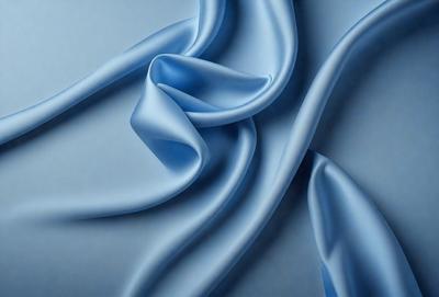 The primary subject of the image is a blue fabric, possibly a piece of silk, that is rolled up and displayed. The setting is a white background, which provides a clean and uncluttered environment for the fabric to be showcased. The visual style of the image is a close-up of the fabric, highlighting its texture and color. The dominant colors in the image are blue and white, creating a calm and serene atmosphere.