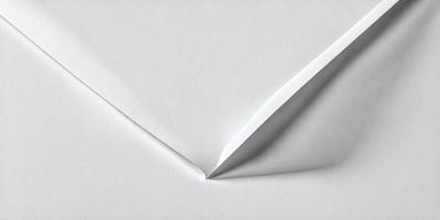 The primary subject of the image is a white envelope with a folded corner. The envelope is sitting on a table, and the setting appears to be indoors. The visual style of the image is a close-up of the envelope, showcasing its details. The colors in the image are predominantly white, giving it a clean and simple appearance.