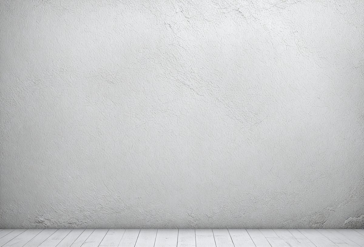 The primary subject of the image is a white wall with a grey texture. The setting is a room with a white floor. The visual style is a photo, and the colors and mood are predominantly white and neutral.