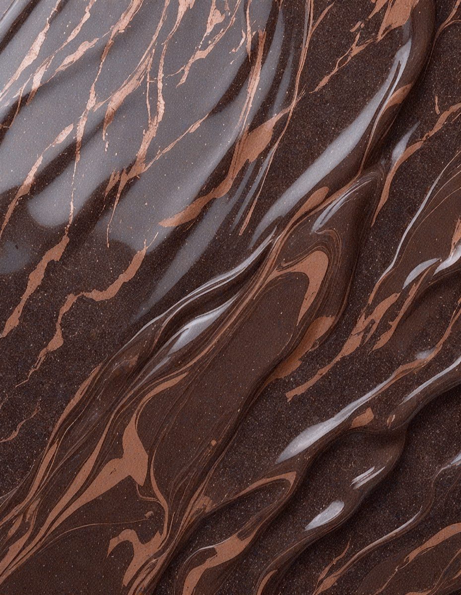 The primary subject of the image is a close-up of a chocolate-covered surface, possibly a chocolate bar or a chocolate-covered item. The setting is a table, and the visual style appears to be a close-up of the chocolate, showcasing its texture and appearance. The colors in the image are predominantly brown, which is the color of the chocolate. The overall atmosphere of the image is rich and indulgent, as it highlights the delicious and tempting nature of the chocolate.