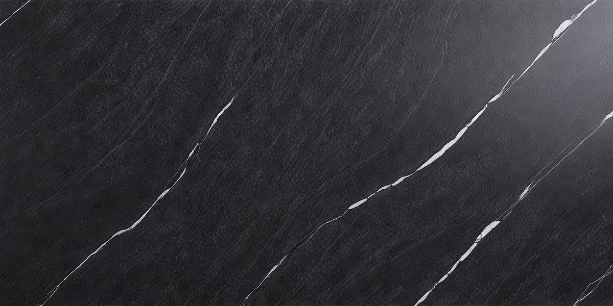 The primary subject of the image is a black marble countertop. The setting is a kitchen, with the countertop being the main focus of the scene. The visual style is a close-up of the marble countertop, showcasing its texture and details. The colors and mood of the image are predominantly dark, with the black marble countertop being the main source of contrast and visual interest.