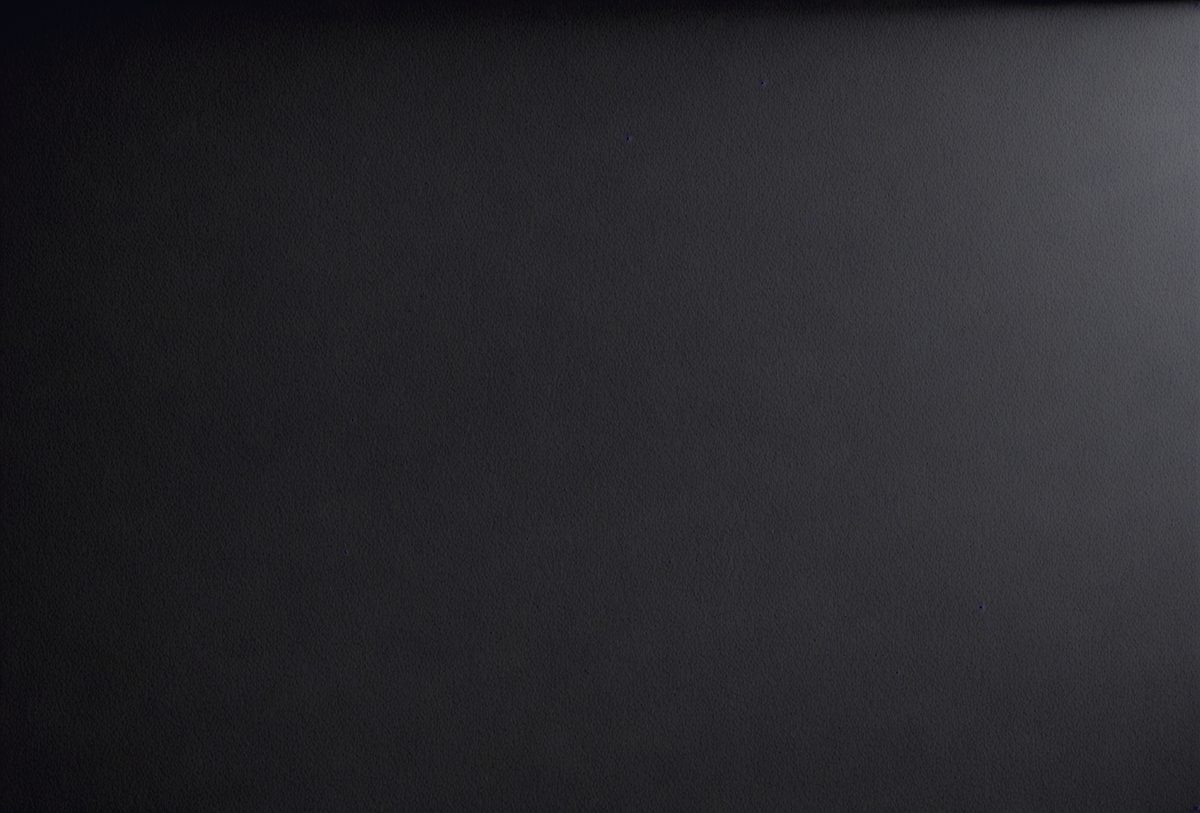 The primary subject of the image is a black background with a white dot pattern. The setting is a dark room, and the visual style is a black and white photo. The dominant colors are black and white, creating a moody and dramatic atmosphere.